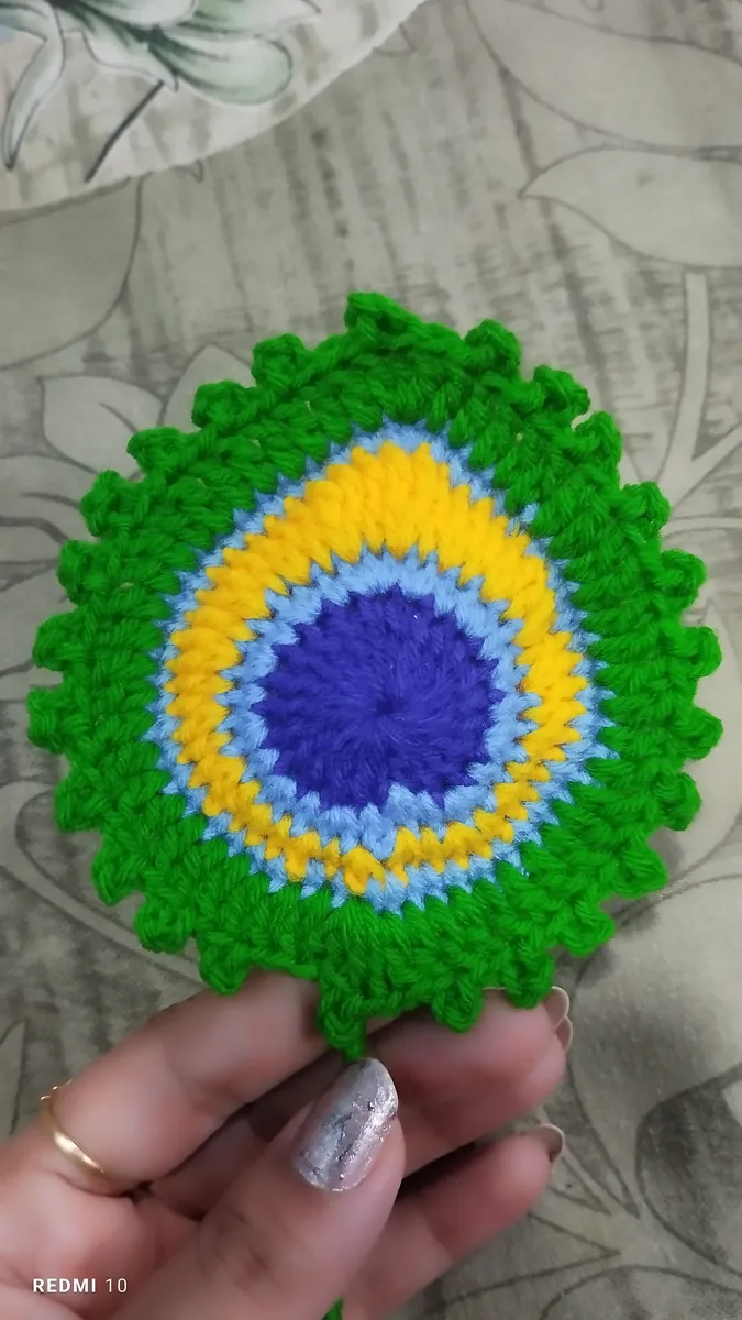 Handmade crochet peacock coaster in green, blue & yellow